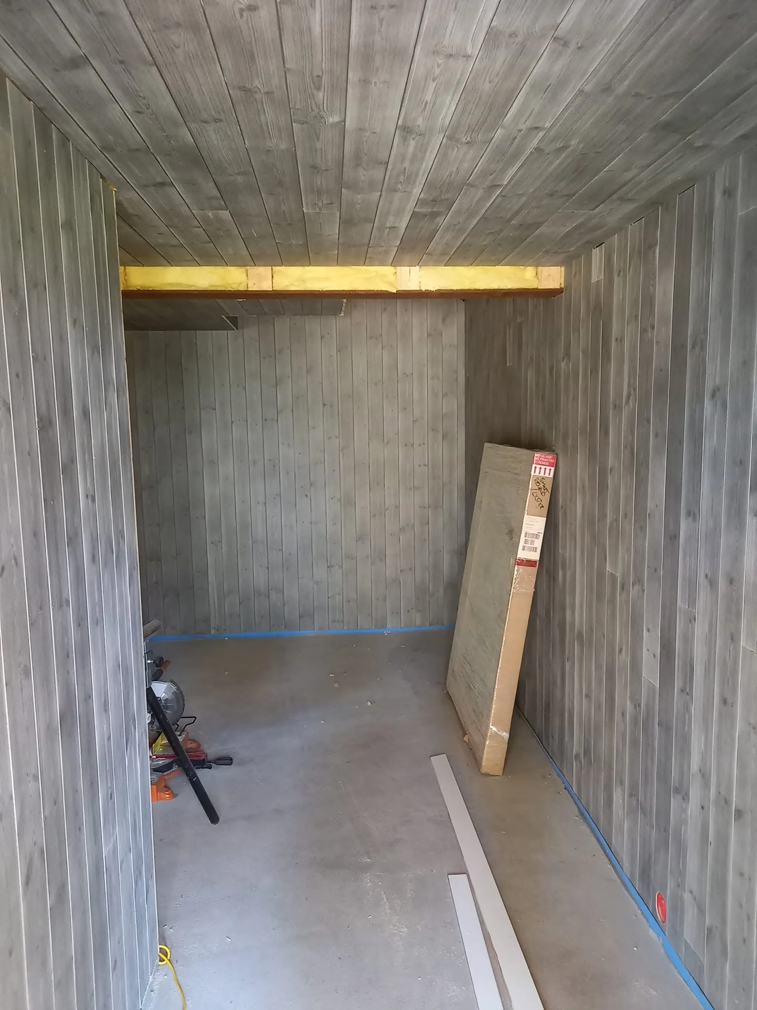Kjellerrom med gråmalt panel klart for gulvlegging