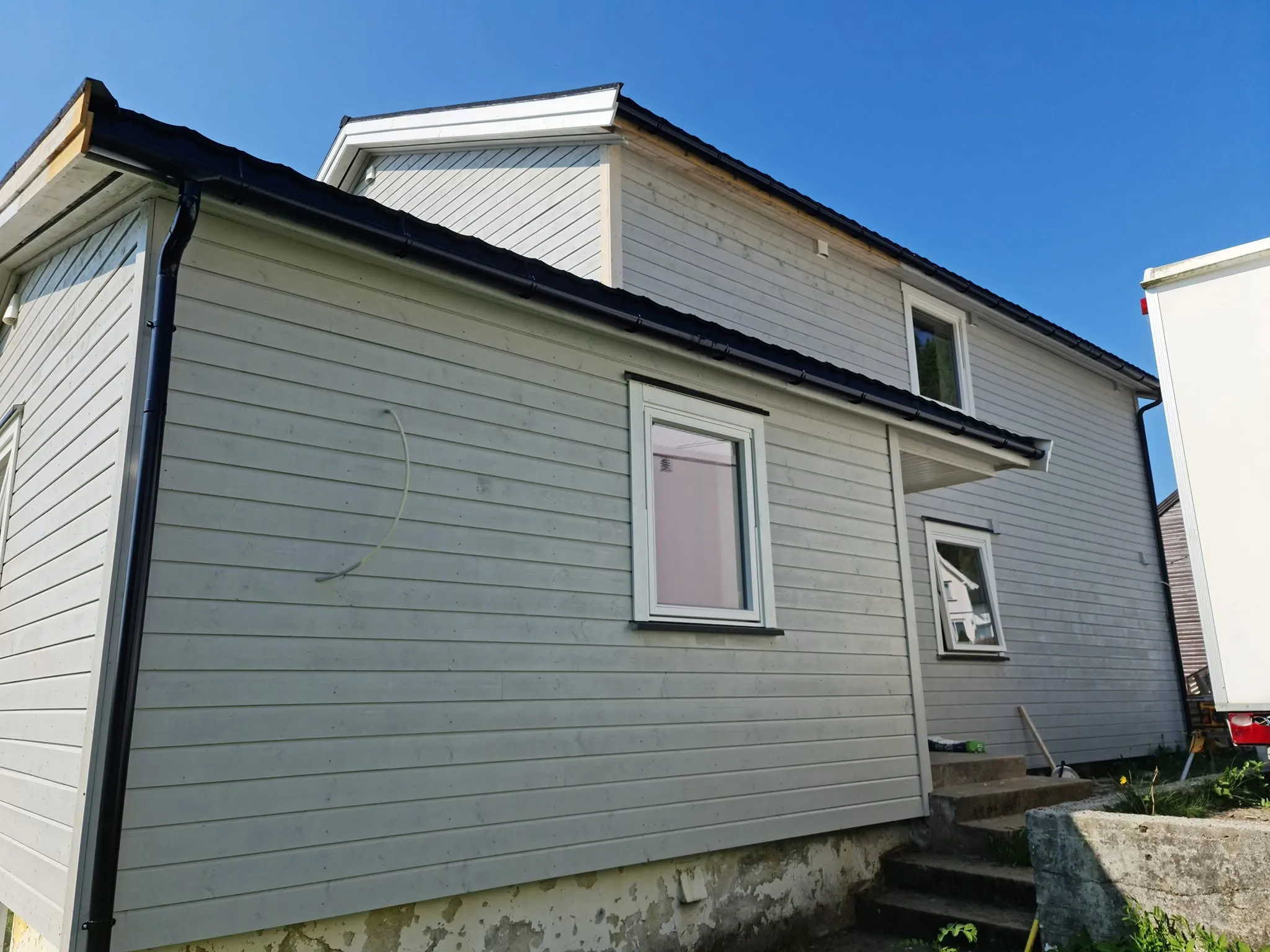 Bolig med ny lys kledning, nye vinduer og svarte takrenner