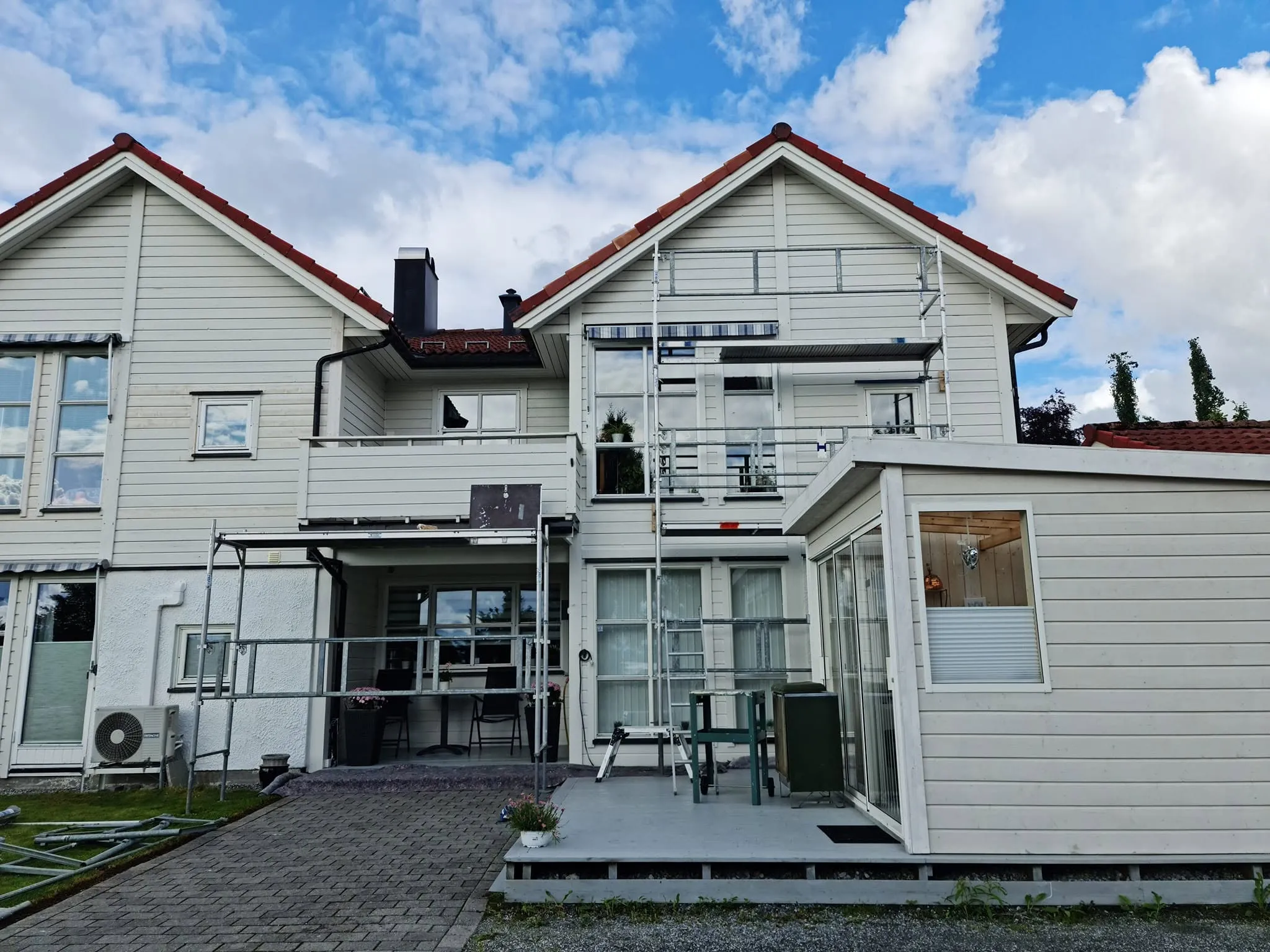 Stillas satt opp langs hvit bolig med terrasse og vinterhage