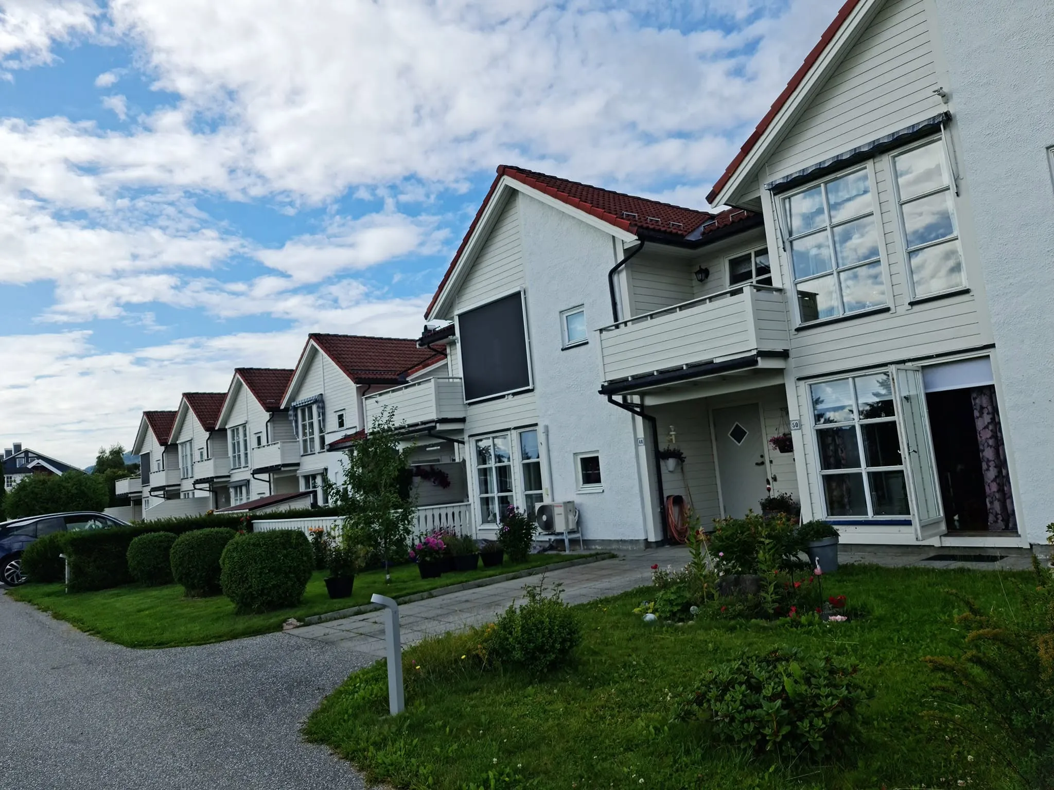 Rekke med hvite boliger med røde tak og markiser