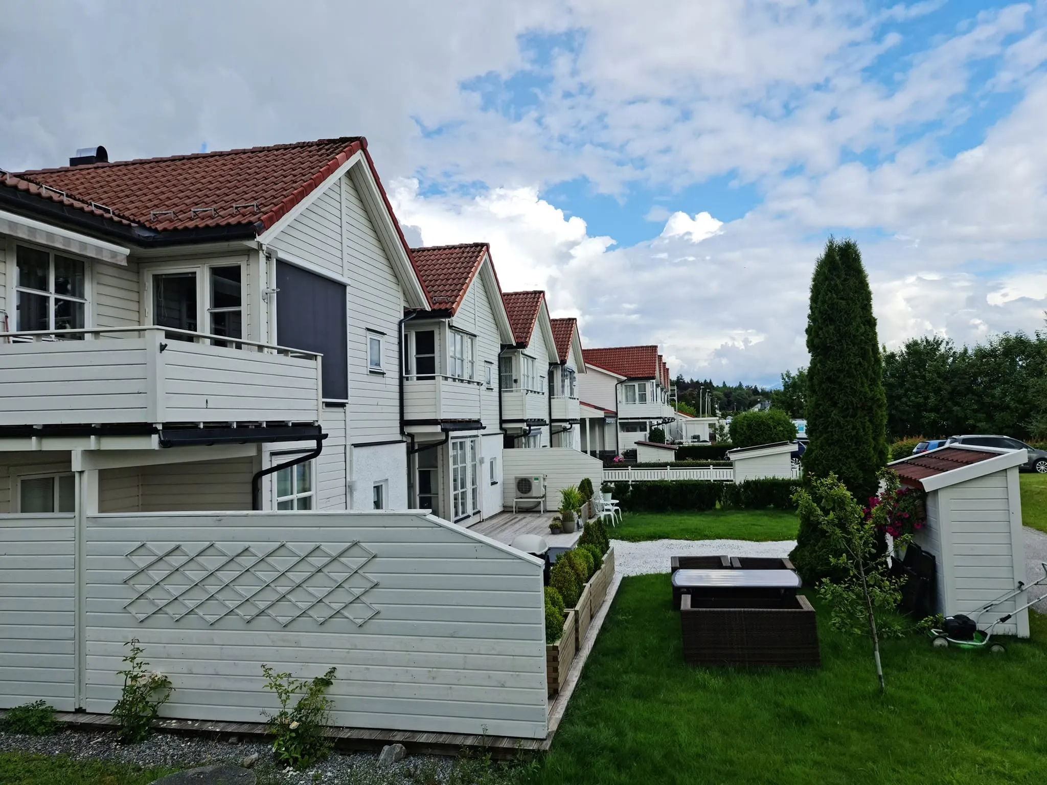 Bakside av rekkehus med hager, levegger og boder