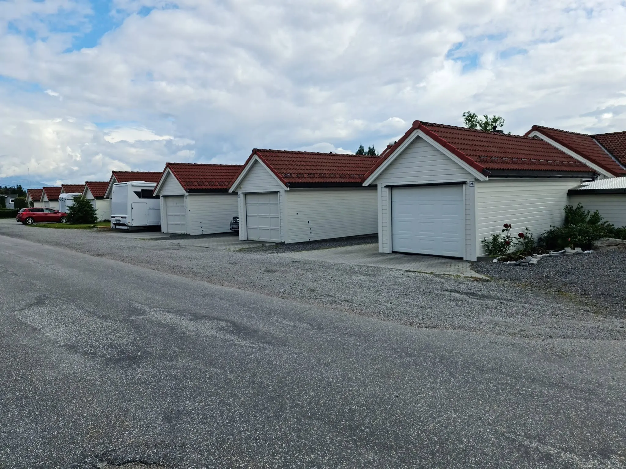 Rekke med hvite garasjer med røde tak i boligfelt