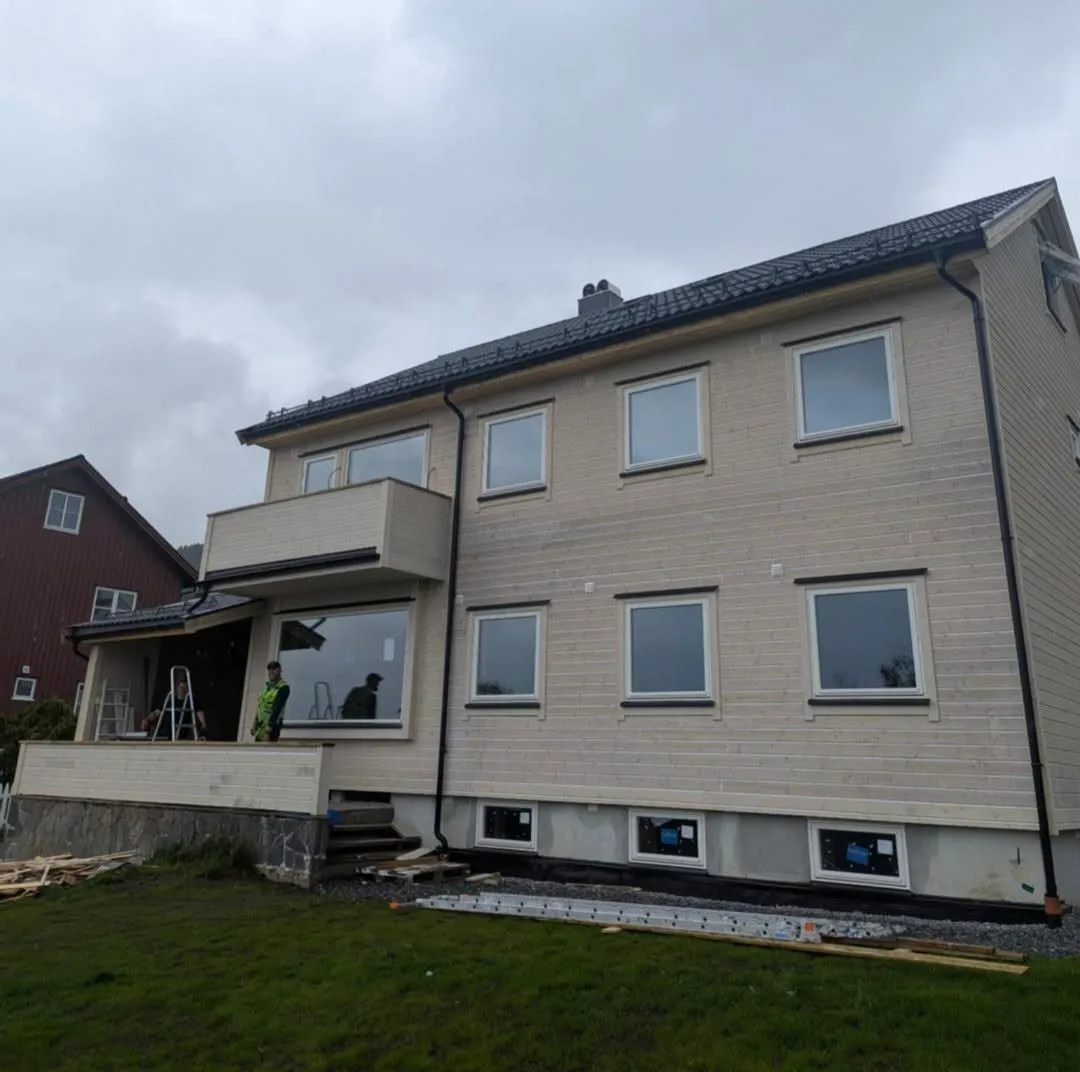 Bolig med ferdig ny kledning, nytt tak og håndverkere på verandaen